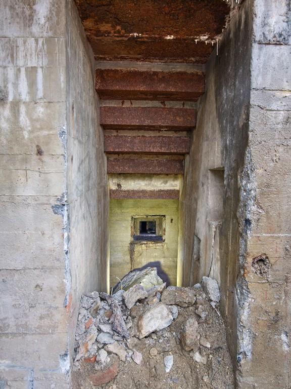 Vue de l'entrée sud : l'escalier d'accès est partiellement remblayé. Au fond, l'ouverture de tir blindée (coffrage en bois est en place)