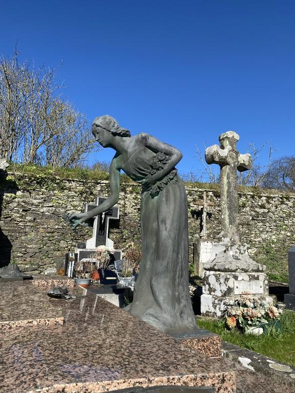 Statue tombale : Jeune femme déposant une fleur sur une tombe, cimetière (Josselin)