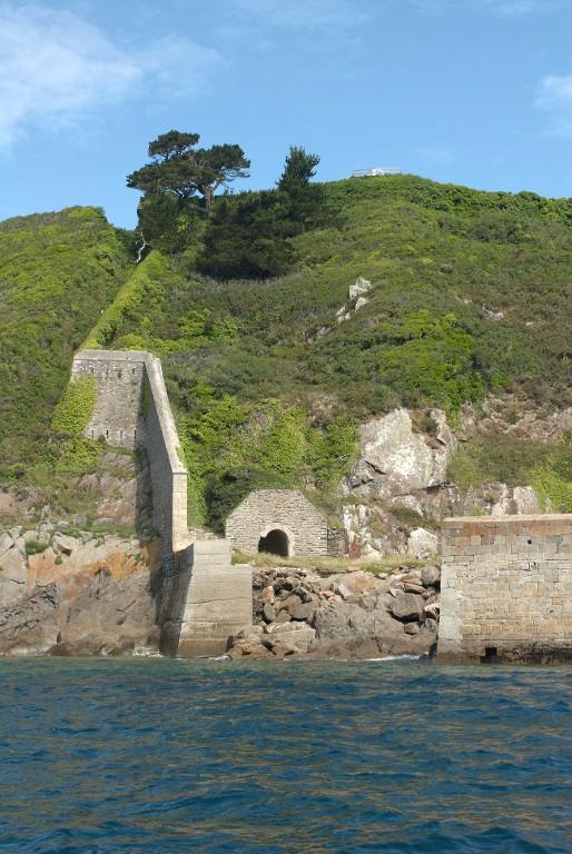 Vue de l'extrémité ouest de la batterie basse du Mengant depuis la mer (état en 2009). Au centre, l'abri de jour du projecteur. La branche tombante crénelé monte jusqu'à la batterie haute
