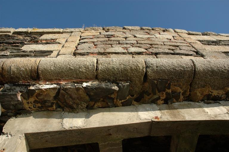 Vue de détail du parapet au-dessus de la brèche ouest : maçonnerie de pierre de taille de granite gris et de gneiss gris foncé (état en 2005). Marquant la jonction entre l'escarpe et le parapet, le cordon en granite gris. L'embrasure est bouchée